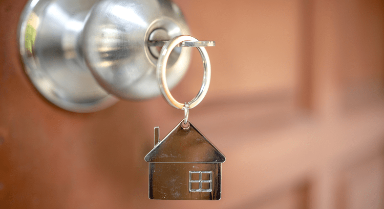 A house-shaped keychain hanging from a key in a front door