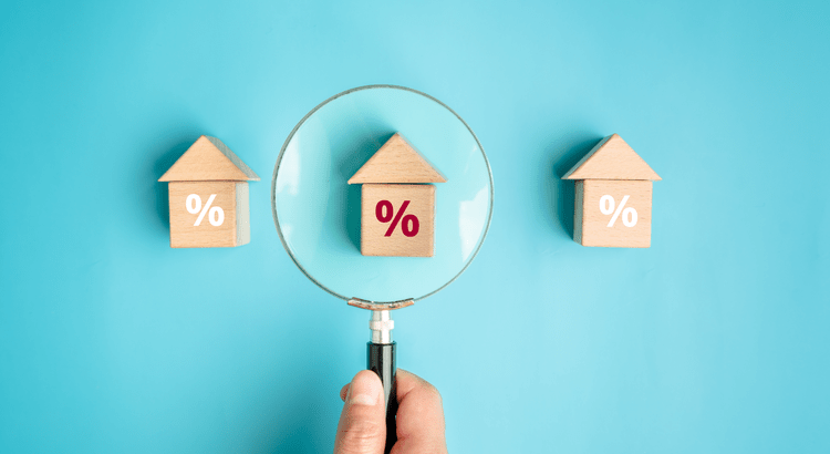 Miniature houses with percentage symbols and a magnifying glass