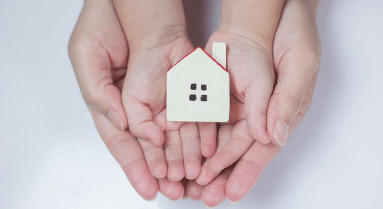 Hands gently holding a small model home